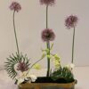 A group of flowers in a container on top of a table.